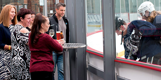 Guests watching an ice hockey game at a rinkside cocktail style function