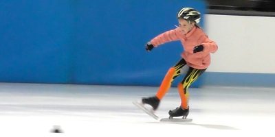 Young girl speed skater doing crossovers on the ice.